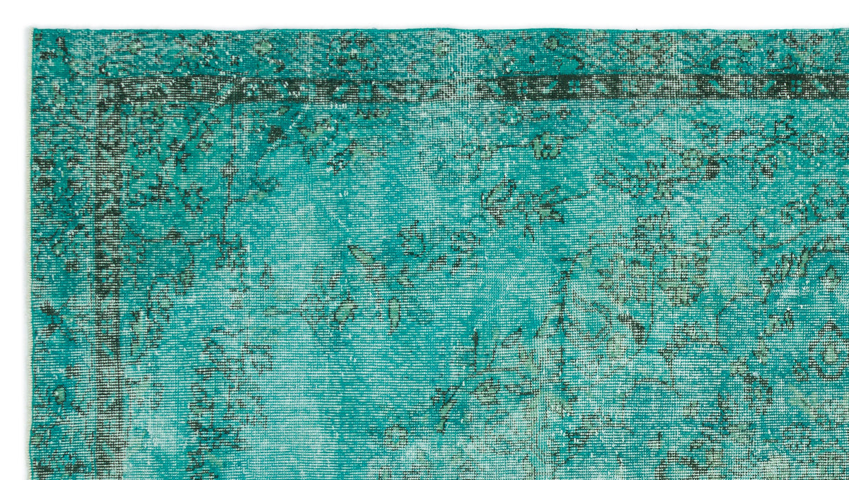 Teal and black distressed traditional rug with a faded floral border and central medallion pattern.
