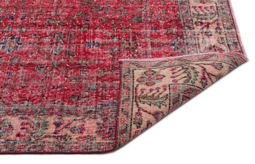 Load image 1 in gallery view. Red and beige vintage-style rug with a distressed floral medallion pattern and a folded corner on a white background.
