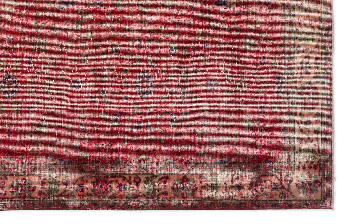 Distressed red traditional rug with a faded floral medallion pattern and a wide, ornate beige border.