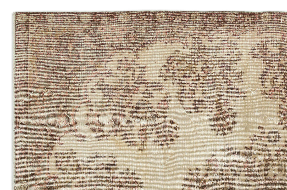 Beige and brown vintage-style rug with a distressed floral medallion pattern and a decorative border.