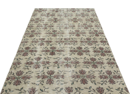 Load image 1 in gallery view. Beige vintage-style rug with a repeating floral medallion pattern in muted red and green tones.