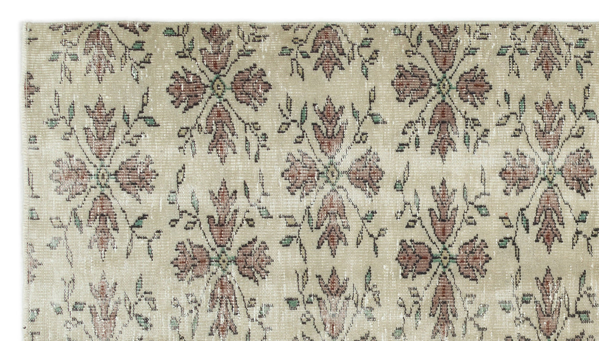 Beige rug with a repeating distressed floral medallion pattern in muted red and green tones.