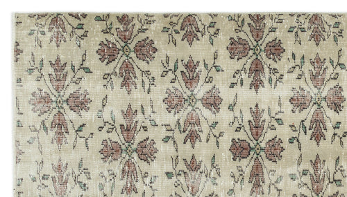Load image 1 in gallery view. Beige rug with a repeating distressed floral medallion pattern in muted red and green tones.