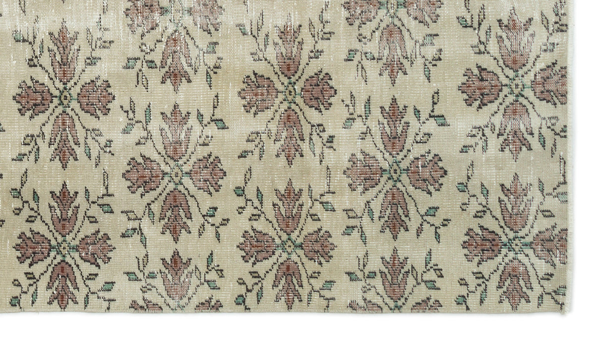 Beige rug with a repeating floral medallion pattern in muted red and green tones.