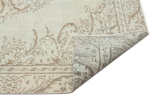 Load image 1 in gallery view. Beige and taupe vintage-style rug with a faded floral medallion pattern, shown with a corner folded over.