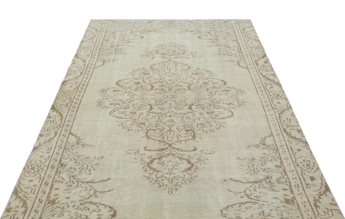 Beige and taupe vintage-style rug with a central floral medallion and ornate border on a white background.