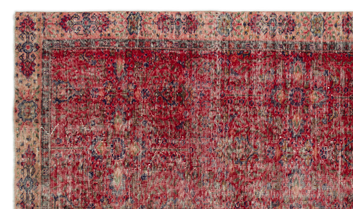 Distressed red and pink traditional rug with a faded floral medallion pattern and dark blue border details.