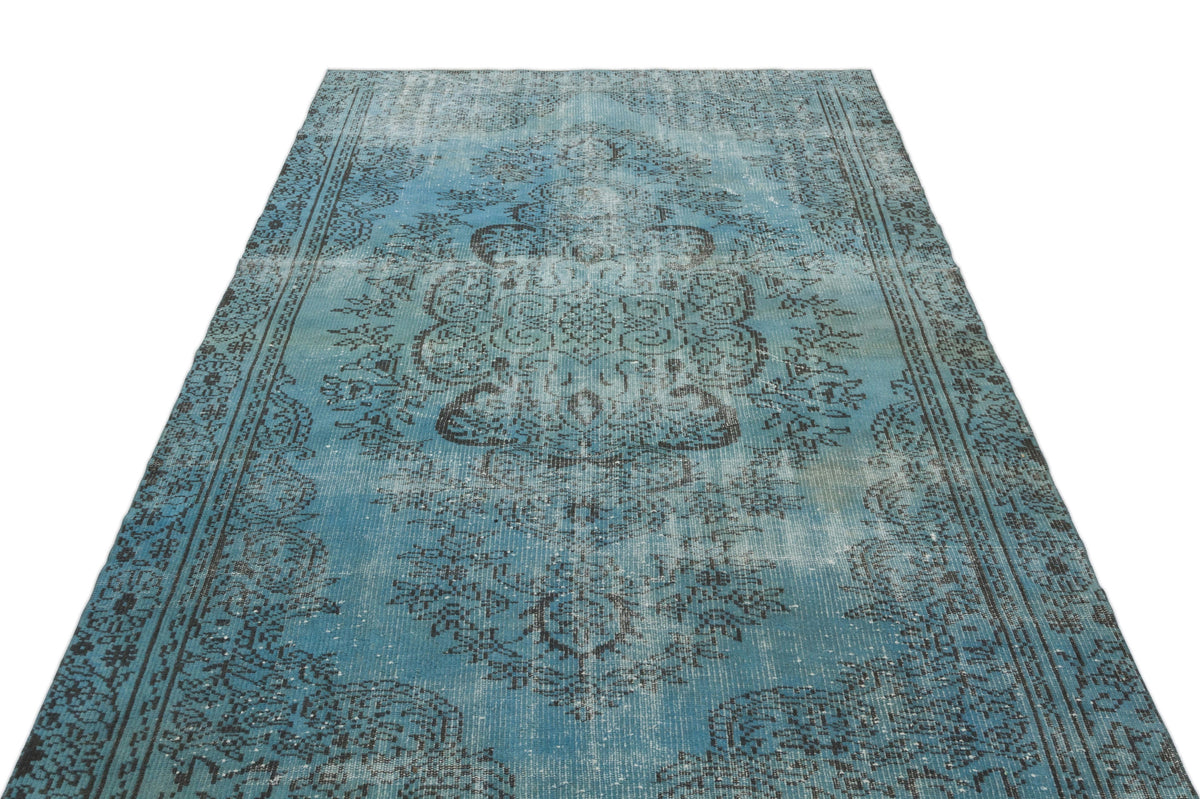 Distressed turquoise and charcoal rug with a traditional central medallion and ornate border pattern.