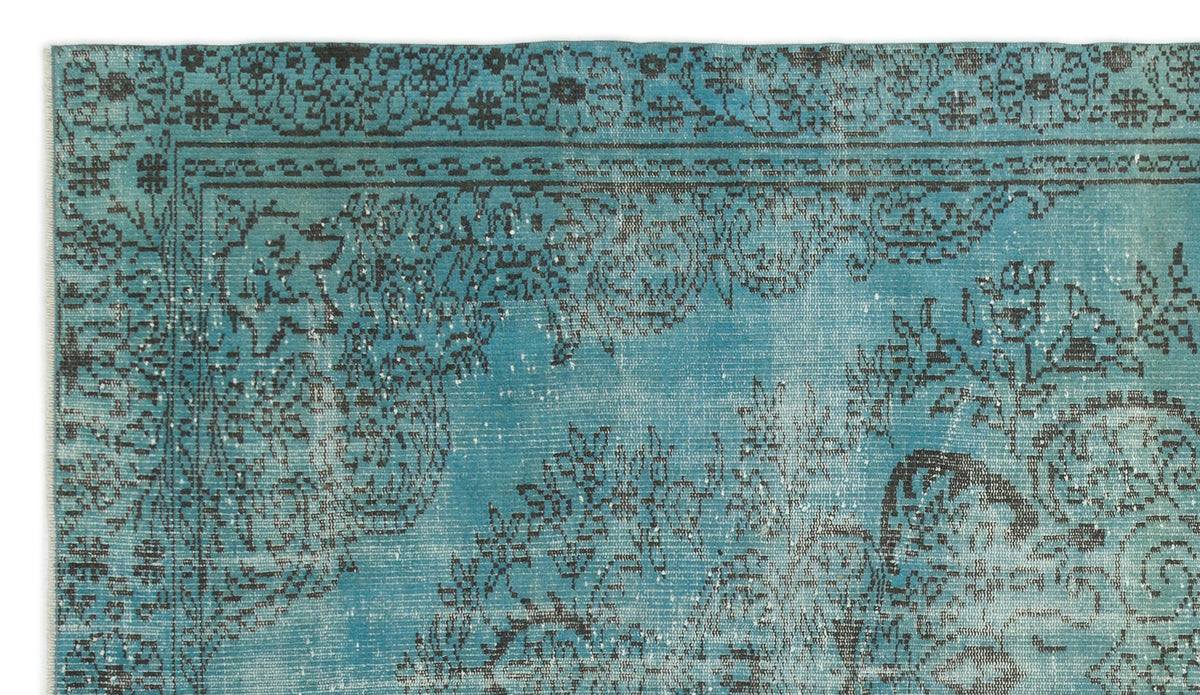 Turquoise rug with a distressed black floral medallion pattern and a decorative border.