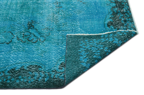 Load image 1 in gallery view. Distressed turquoise and teal vintage-style rug with a faded floral medallion pattern, shown with a folded corner.