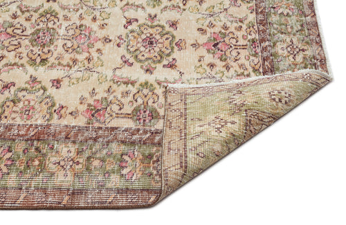 Load image 1 in gallery view. Beige rug with a distressed floral medallion pattern in pink, green, and brown, featuring a folded corner.