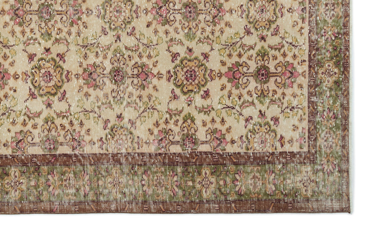 Beige traditional rug with a distressed floral medallion pattern in pink, green, and brown, featuring a wide border.