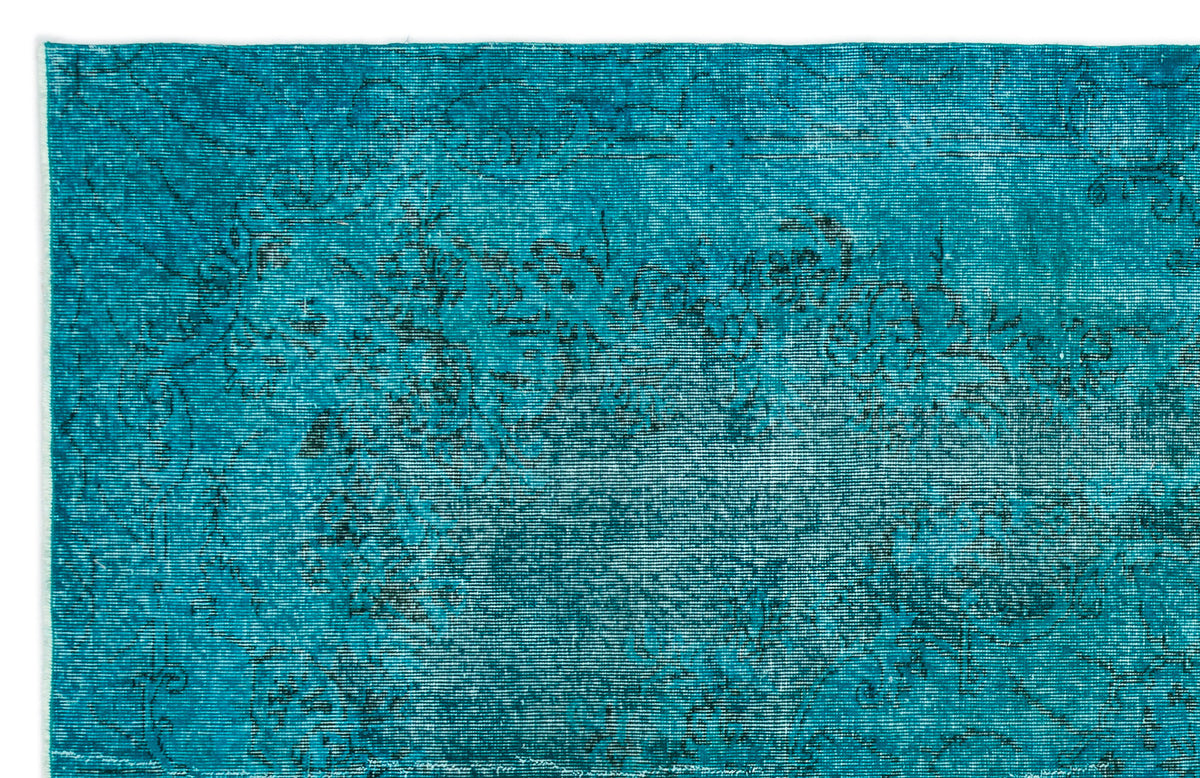 Teal distressed rug with a faded black floral medallion pattern on a white background.