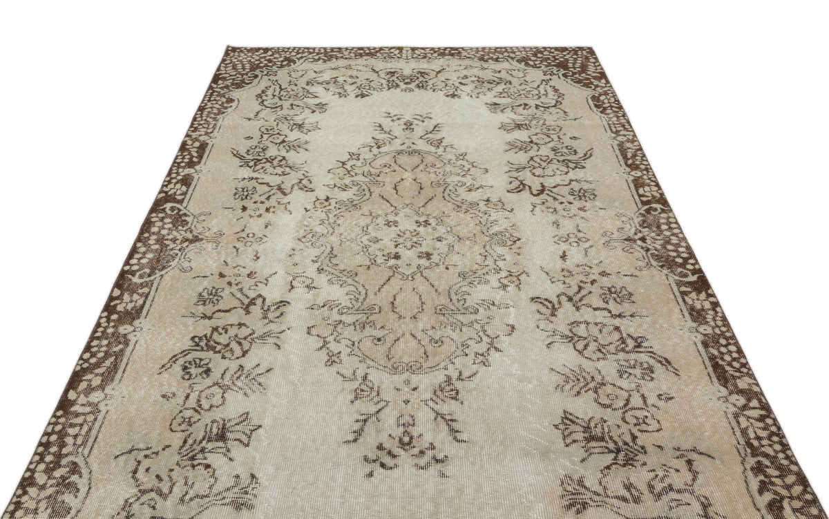 Beige and brown vintage-style rug with a central floral medallion and ornate border pattern on a white background.