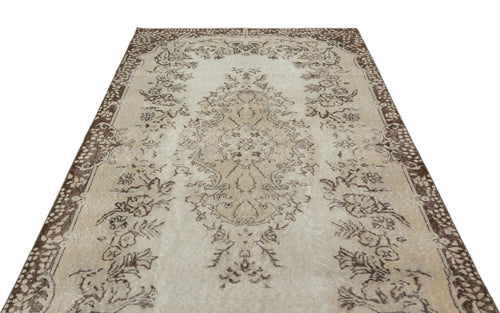 Load image 1 in gallery view. Beige and brown vintage-style rug with a central floral medallion and ornate border pattern on a white background.