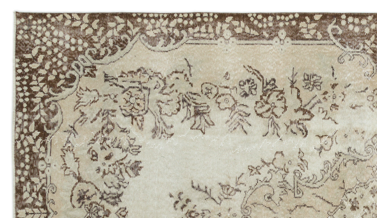 Beige and brown vintage-style rug with a distressed floral medallion pattern and a decorative border.
