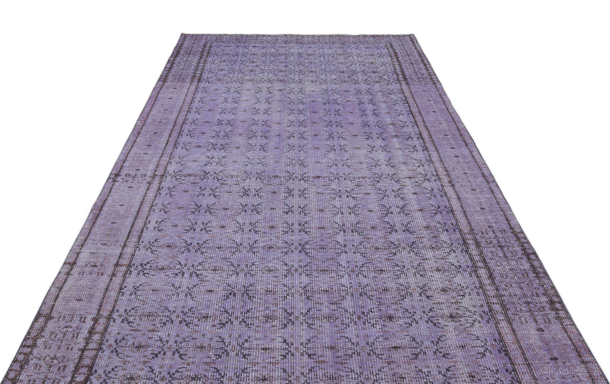 Distressed purple vintage-style rug with a repeating dark grey floral medallion pattern and a bordered edge.