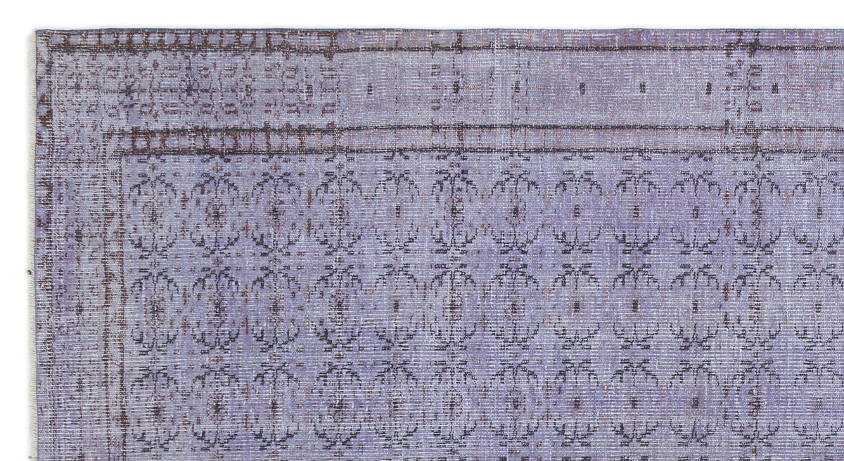 Lavender and dark brown vintage-style rug with a repeating floral medallion pattern and a decorative border.