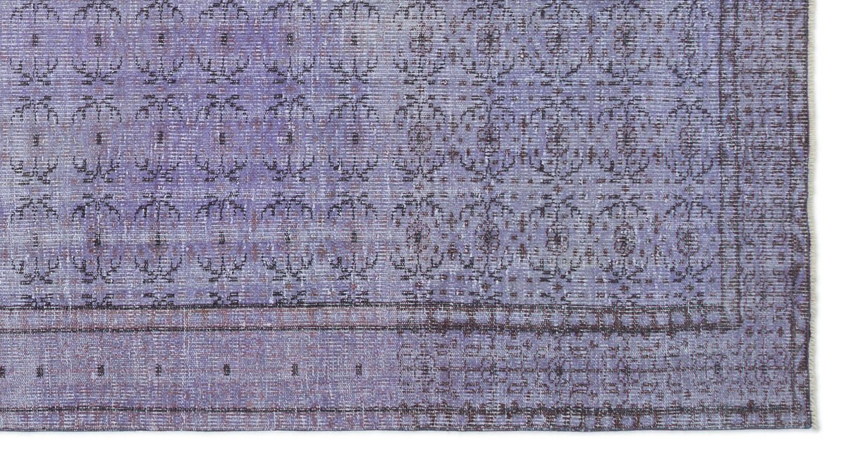 Lavender and dark purple distressed rug with a repeating floral medallion pattern and a bordered edge.
