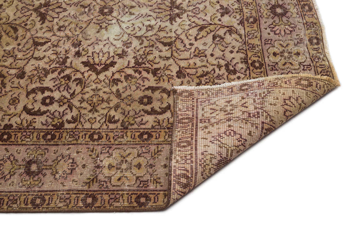 Distressed brown and beige traditional rug with a floral medallion pattern and a folded corner on a white background.