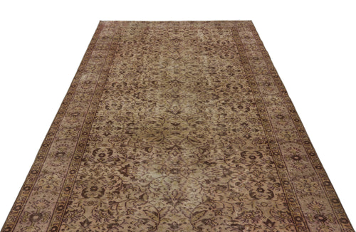 Load image 1 in gallery view. Distressed brown and tan vintage-style rug with an all-over floral medallion pattern and a detailed border.