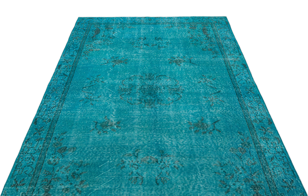 Teal distressed rug with a faded central medallion and ornate border pattern on a white background.