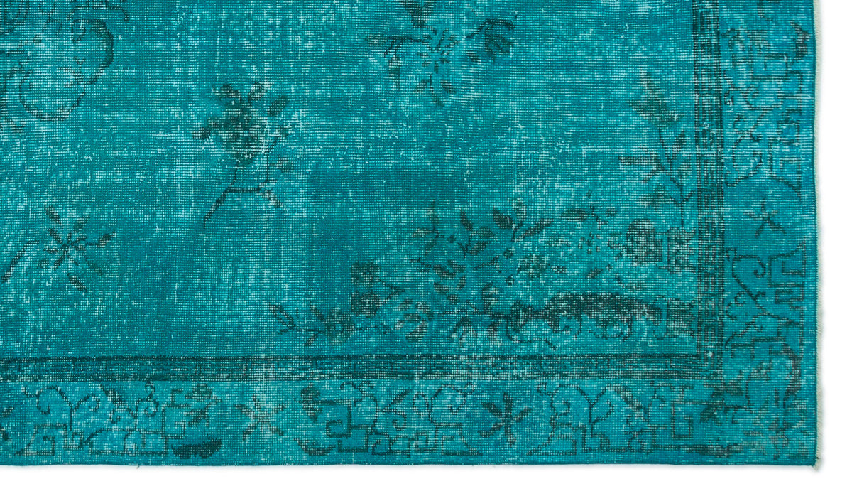 Teal distressed rug with a dark floral pattern and a geometric border.