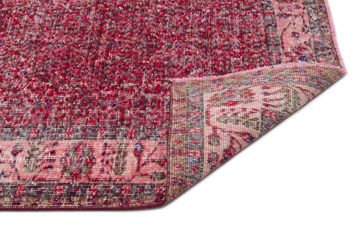 Load image 1 in gallery view. Distressed crimson and pink traditional rug with a floral border, shown with a corner folded over on a white background.