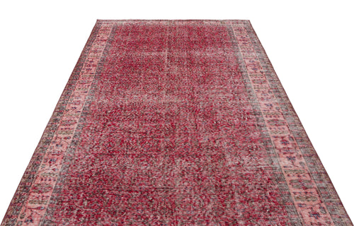 Load image 1 in gallery view. Distressed crimson and pink vintage-style rug with a faded central field and ornate geometric border.