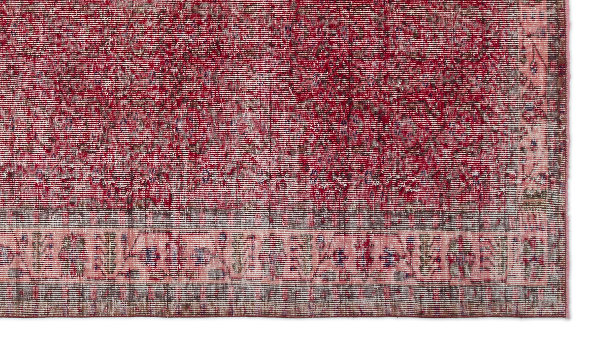 Distressed deep red rug with a faded traditional border pattern and visible woven texture.