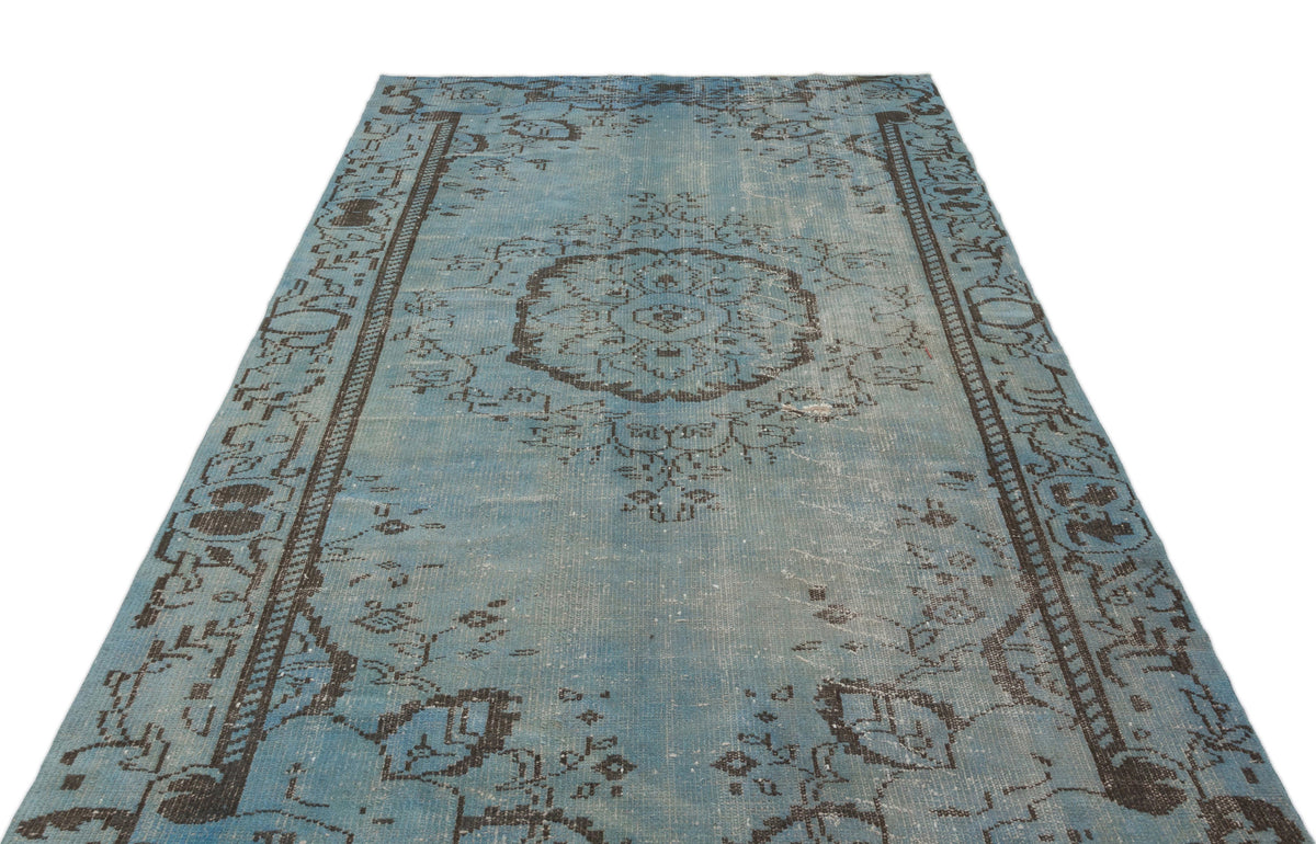 Distressed light blue rug with a dark brown central medallion and ornate border pattern on a white background.
