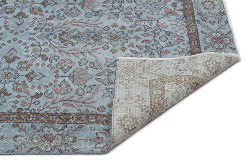 Load image 1 in gallery view. Light blue, brown, and pink distressed traditional rug with a floral medallion pattern, shown with a corner folded over.