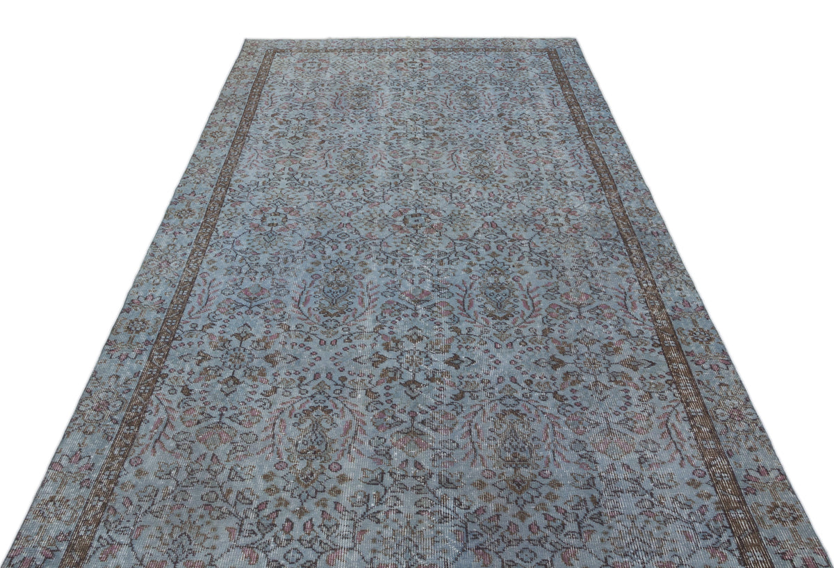Light blue distressed rug with a traditional floral medallion pattern and a dark brown border on a white background.