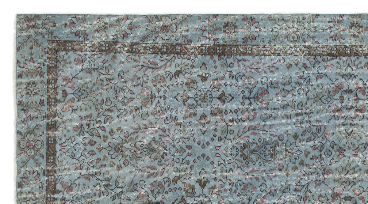Light blue traditional rug with a distressed floral medallion pattern and a dark brown border.