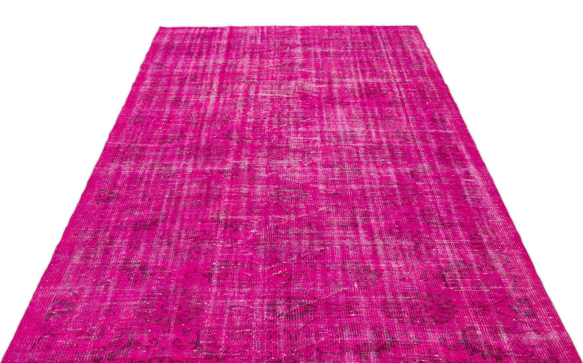 Fuchsia distressed vintage-style rug with a faded floral medallion pattern on a white background.