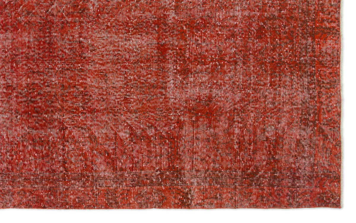 Distressed brick red rug with a faded, textured vintage pattern.