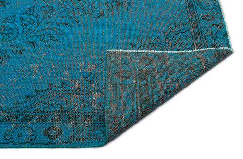 Load image 1 in gallery view. Turquoise and charcoal distressed rug with a traditional floral medallion pattern, shown with a folded corner.