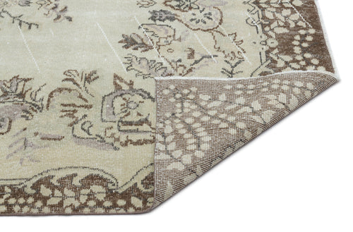 Load image 1 in gallery view. Beige and brown distressed rug with a faded floral medallion pattern, shown with a corner folded over.