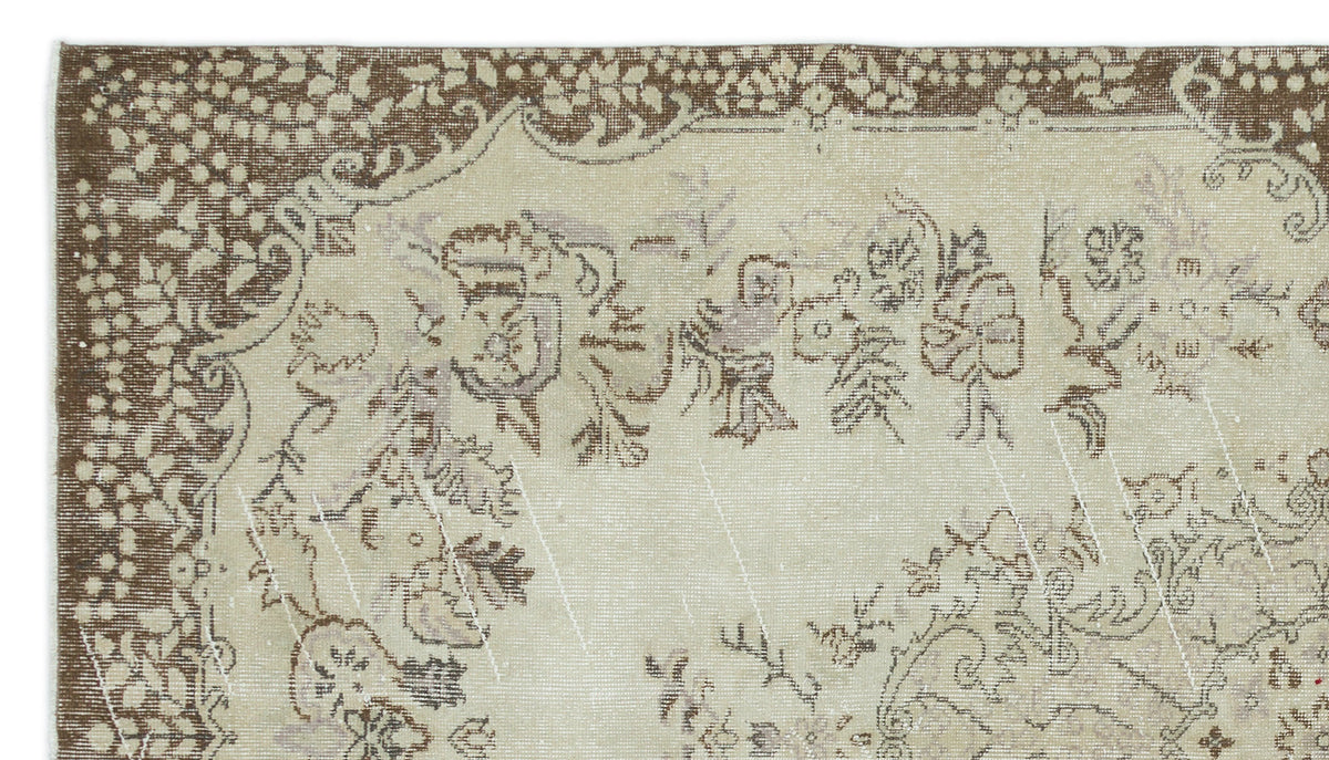 Beige and brown vintage-style rug with a distressed floral medallion pattern and a decorative border.