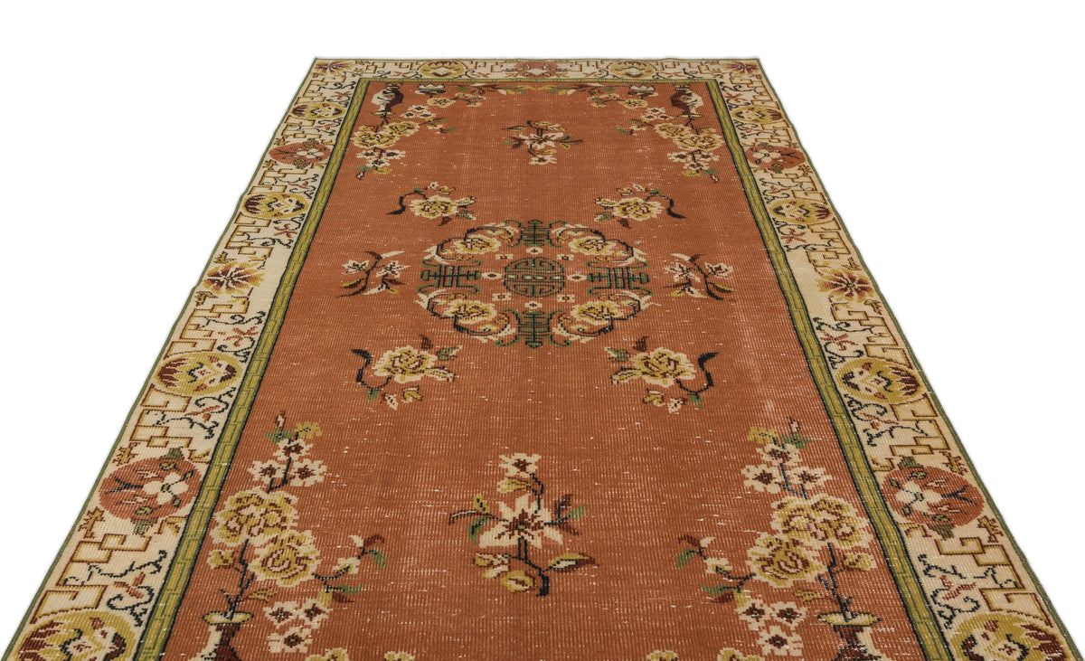 Terracotta runner rug with a central floral medallion, scattered floral motifs, and a geometric border on a white background.