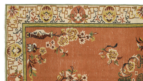 Load image 1 in gallery view. Terracotta rug with floral branch motifs and a cream geometric border, isolated on a white background.