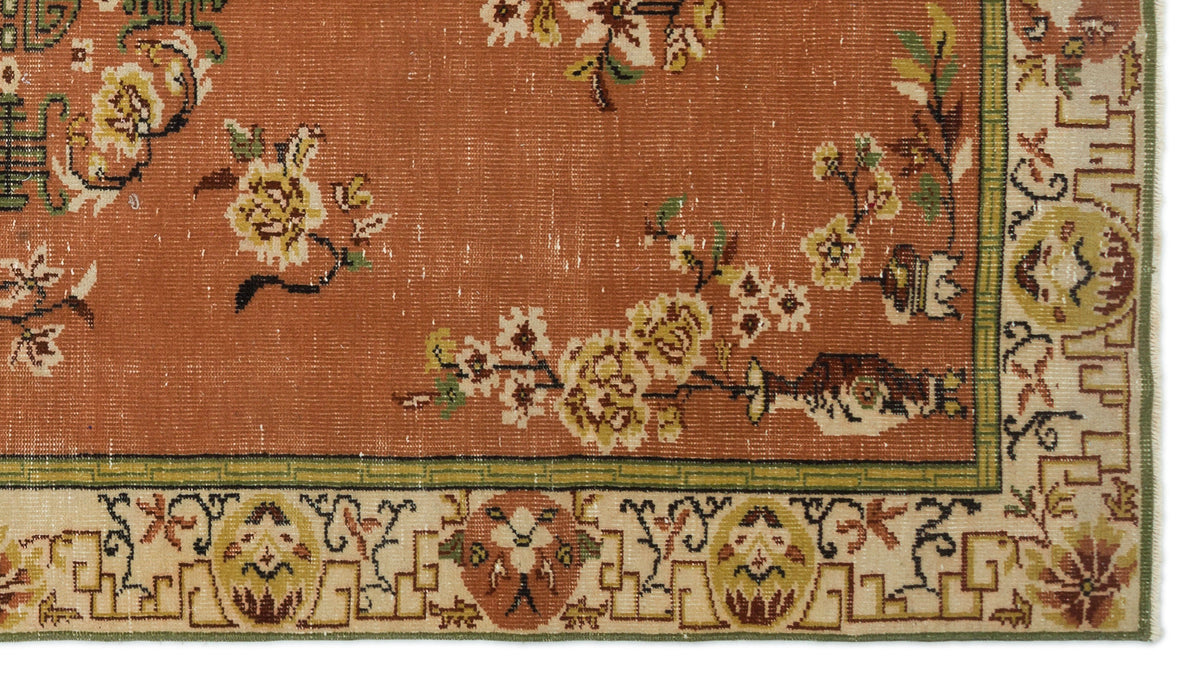 Terracotta rug with yellow floral branches and a cream border featuring geometric and botanical motifs.