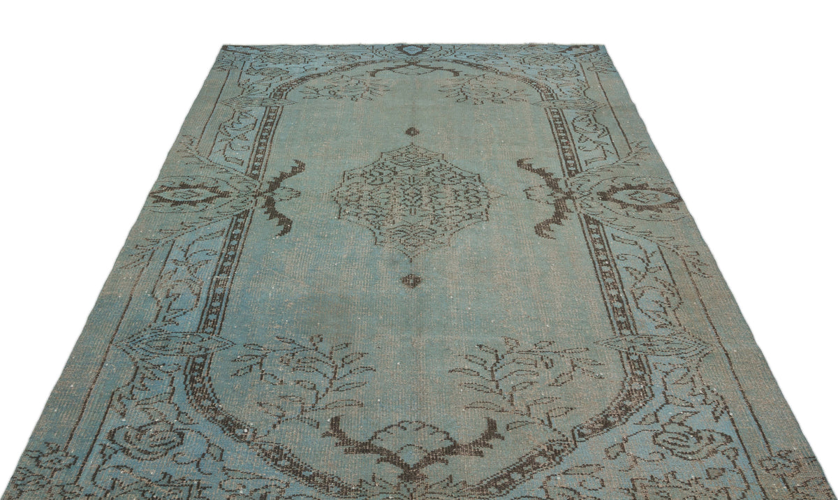 Distressed light blue rug with a dark brown central medallion and traditional floral border pattern.
