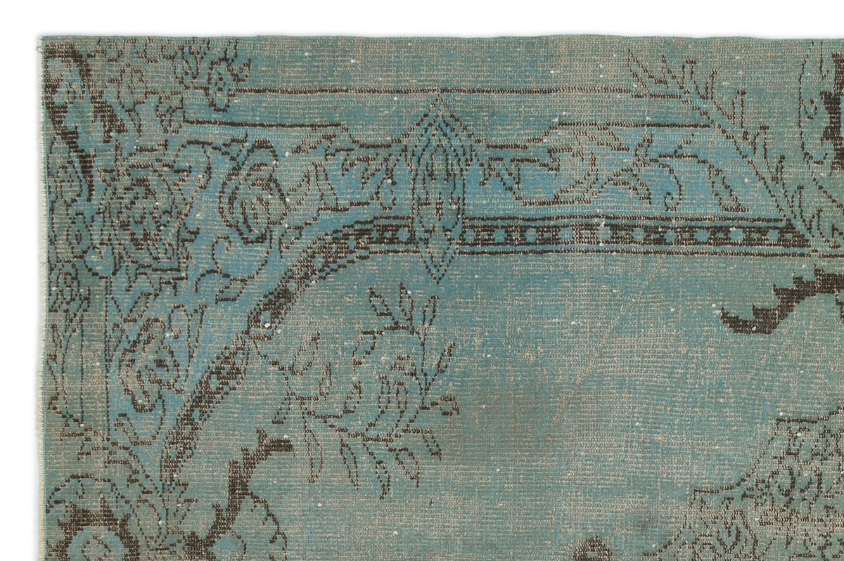Teal and charcoal distressed rug with a traditional floral and geometric border pattern.