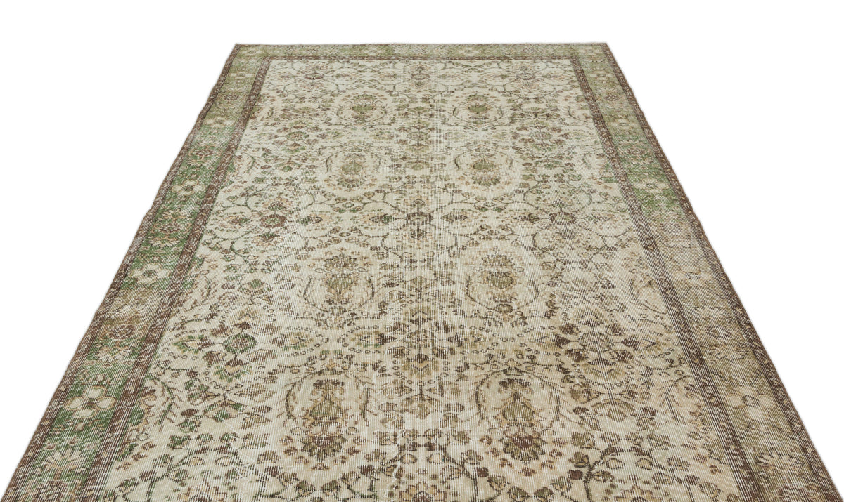 Beige and green vintage-style rug with a distressed floral medallion pattern and a decorative border.
