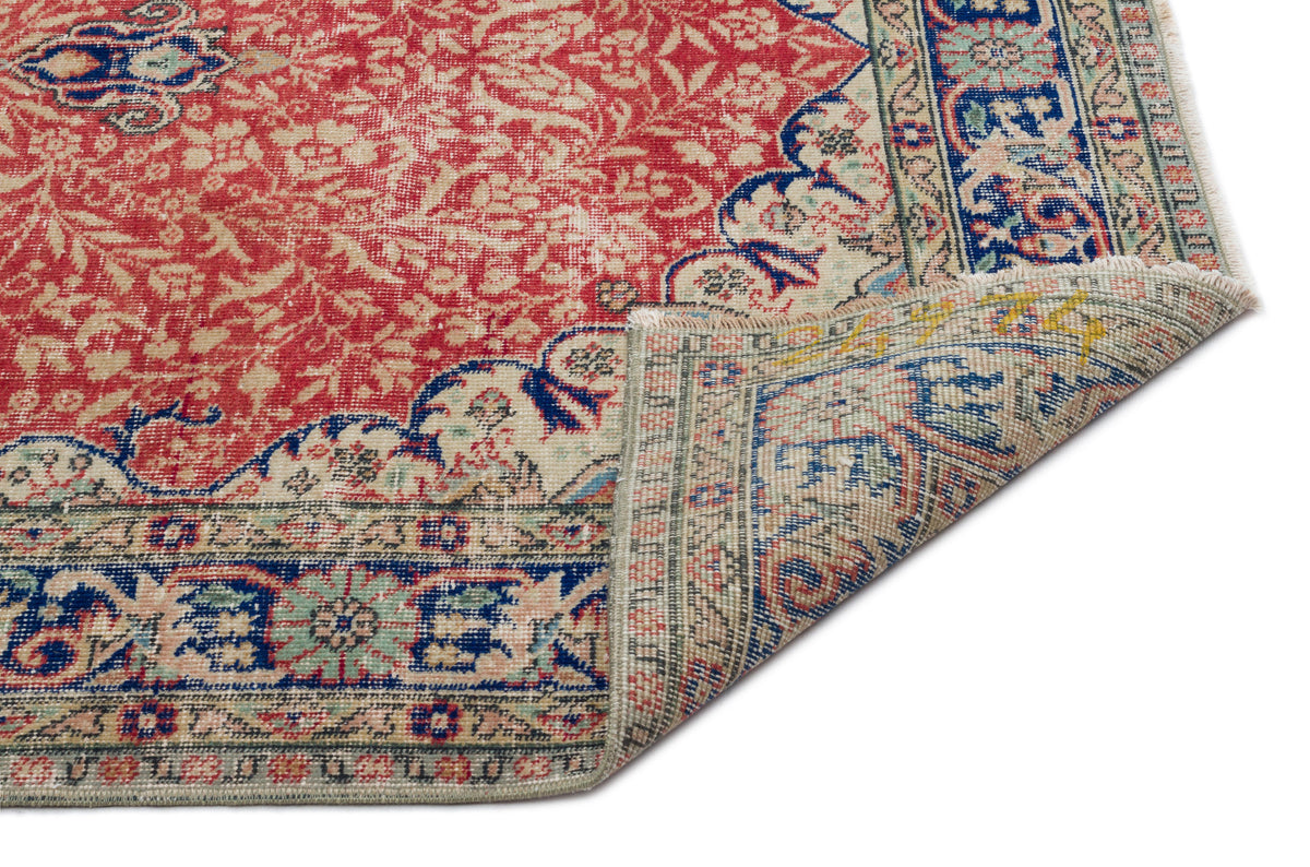 Red and cream traditional Persian-style rug with blue floral borders and a folded corner showing the underside.
