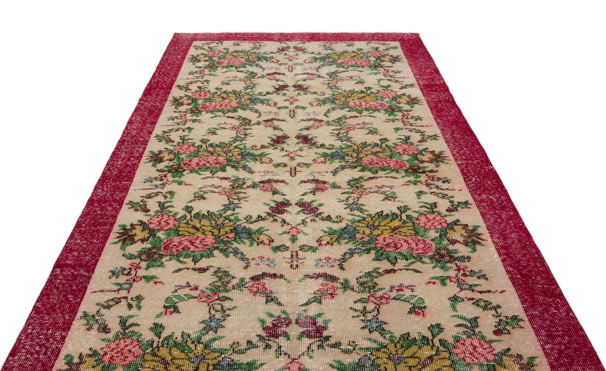 Beige runner rug with a red border and a repeating floral pattern in pink, green, and yellow.