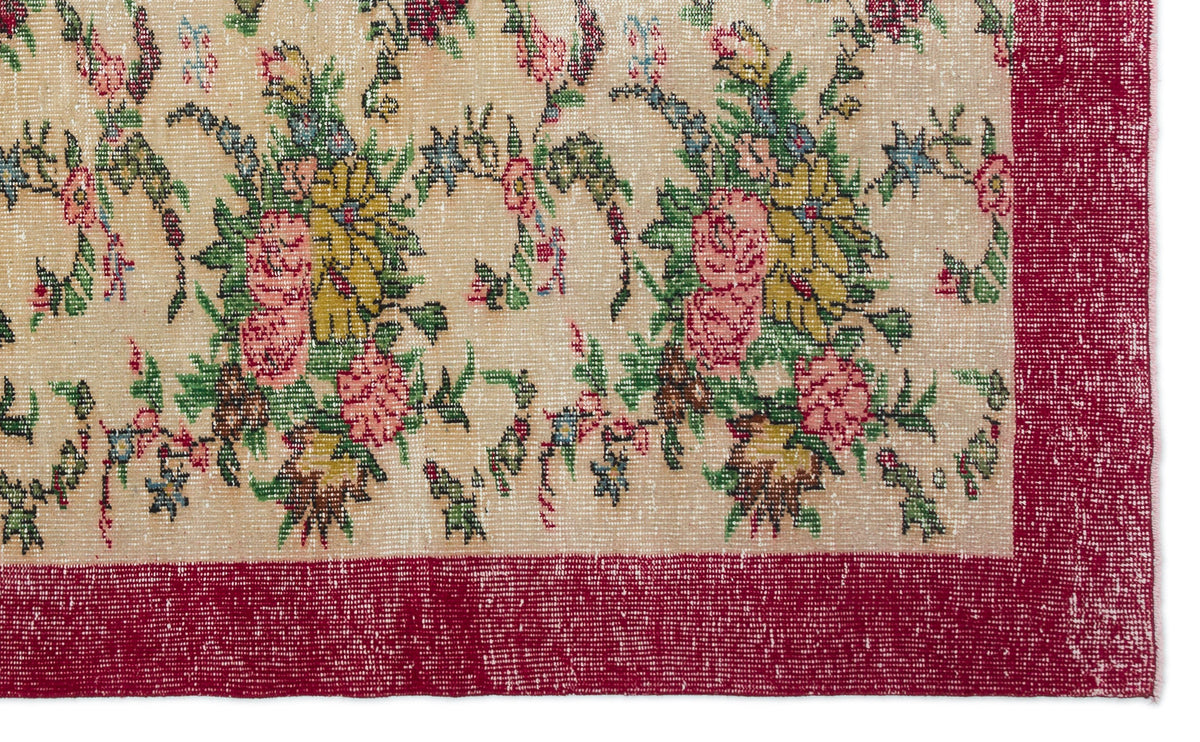 Beige rug with a distressed floral pattern in pink, yellow, and green, featuring a wide, solid red border.