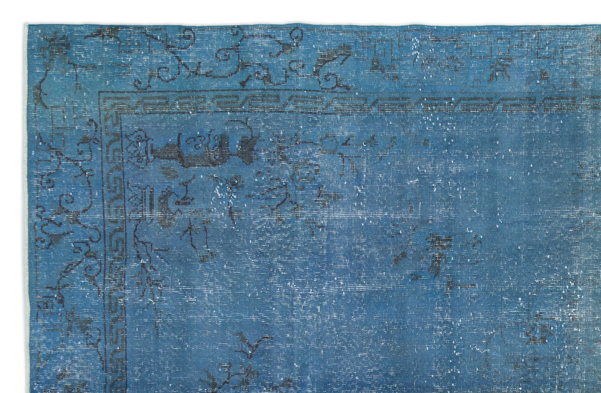 Blue distressed rug with a dark grey floral and geometric border pattern on a white background.
