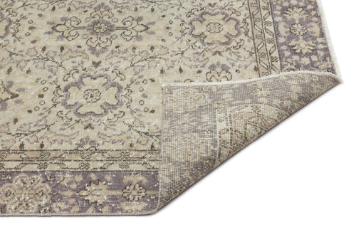 Load image 1 in gallery view. Beige and grey traditional rug with a distressed floral medallion pattern and a folded corner, on a white background.